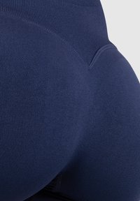 Leggings azul marino fabricados con material elástico, con un diseño de cintura alta y una superficie suave y texturizada. Detalles de costura visibles.