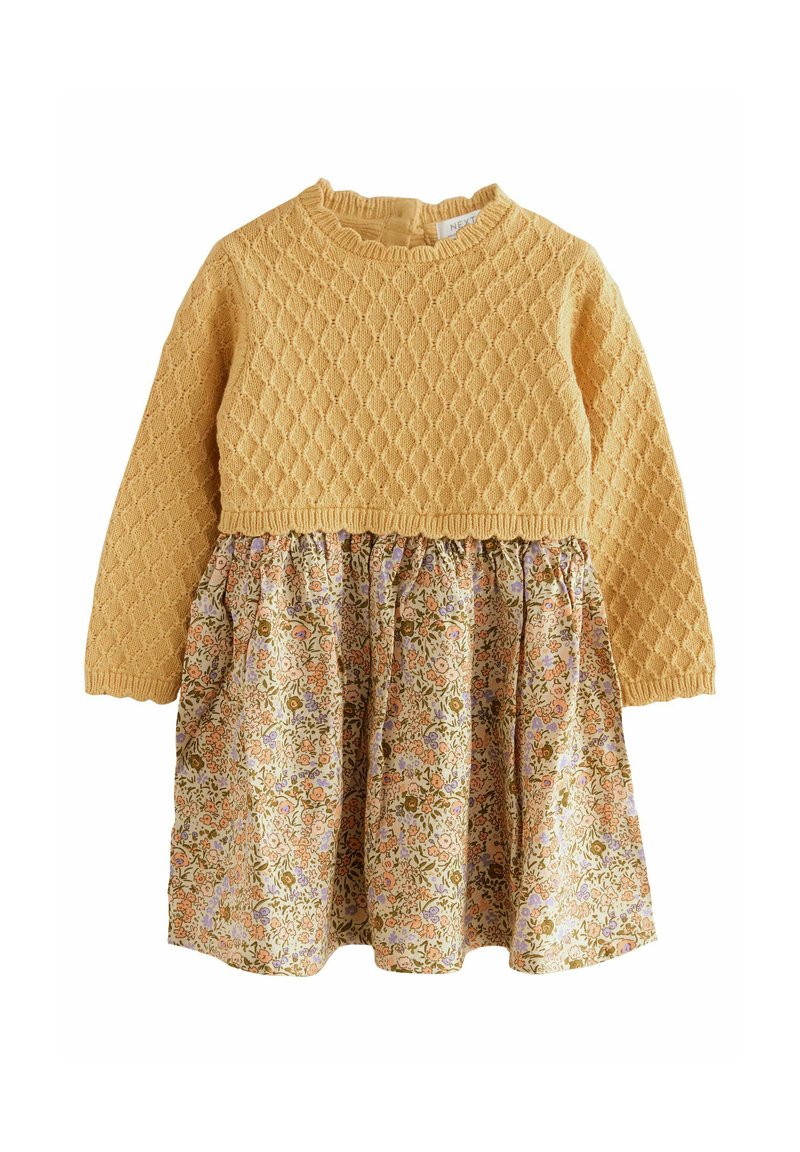 Robe en tricot jaune avec un corsage texturé et une jupe à imprimé floral featuring des fleurs orange et violettes sur un fond clair. Manches longues.