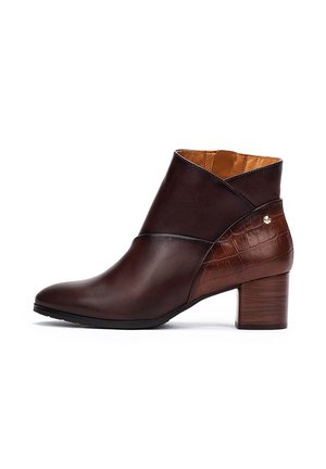 Brown leather ankle boot with a croc-patterned accent, round toe, and a mid-heel. Features a cross strap design and gold logo detail.