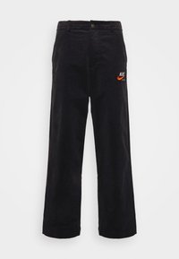 Svarta kordbyxor med rak bendesign. Har en broderad orange Nike-logotyp på högra sidan. Metallknäppning.