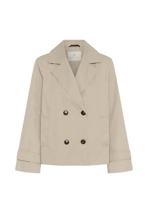 Beige damesblazer met dubbele knoopsluiting, brede revers, twee voorzakken, knoopmanchetten en zwarte knopen.
