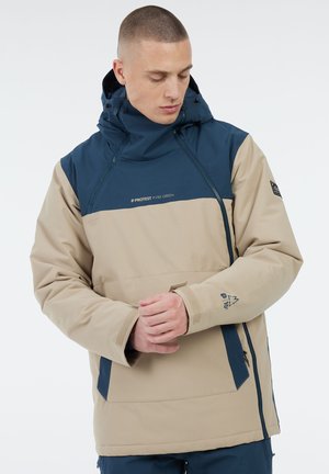 Beige en marineblauwe gewatteerde jas met een ritssluiting aan de voorkant, verstelbare manchetten en logo-accenten. Heeft een ruime pasvorm en een dikke, gestructureerde stof.