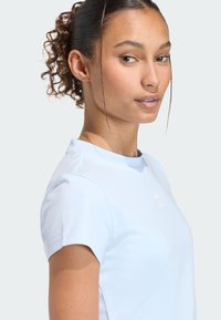 Svetlomodré tričko s krátkym rukávom vyrobené z mäkkej látky s okrúhlym výstrihom a diskrétnym logom na hrudi. Hladká textúra a jednoduchý dizajn.