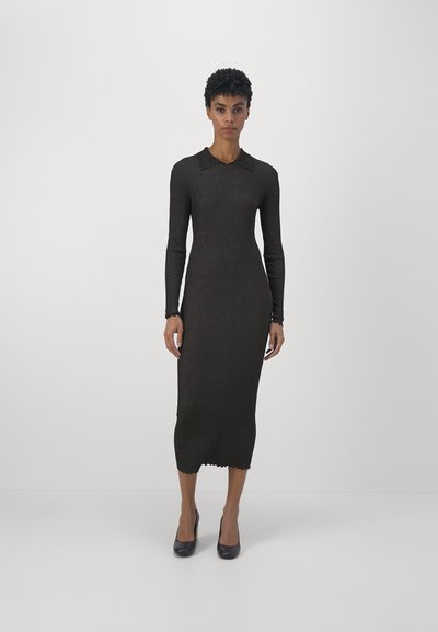 Abito in maglia color marrone scuro, silhouette aderente con maniche lunghe e colletto ondulato. L'orlo è leggermente curvato nella parte inferiore.