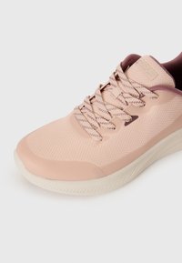 Baskets de sport rose pâle avec tige en maille texturée, accents maroon contrastants et lacets à motifs ; dotées d'une semelle rembourrée et d'un design épuré.