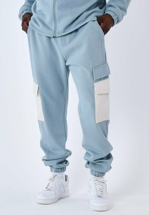 Pantalons cargo bleu clair avec des poignets côtelés, dotés de deux poches latérales crème et d'une coupe décontractée, fabriqués en matière douce à base de coton.
