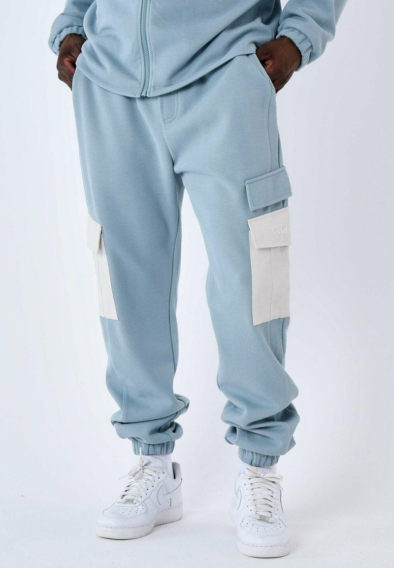Pantaloni cargo joggers azzurri chiari con polsini a coste, dotati di due tasche laterali di colore crema e una vestibilità comoda, realizzati in morbido materiale misto cotone.