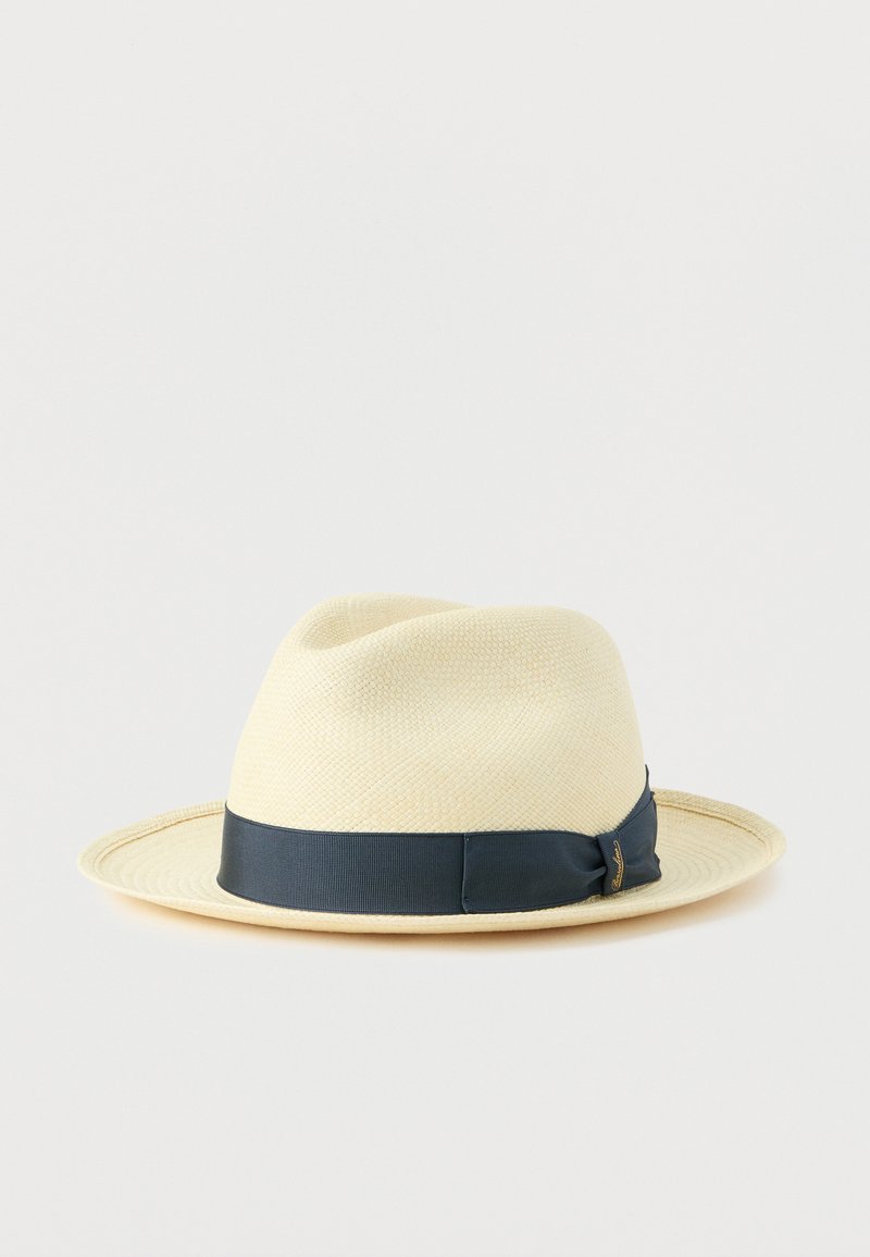 Hut aus Strohfeder, beige Farbe, mit einem marineblauen Ripsband am Rand, leicht gebogener Krempe und strukturierter Oberfläche.