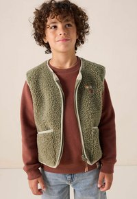 Fleece-Weste in olivgrün, mit Reißverschluss vorne, zwei Fronttaschen, crèmefarbenem Besatz und gestickten Akzenten, getragen über einem braunen Sweatshirt.