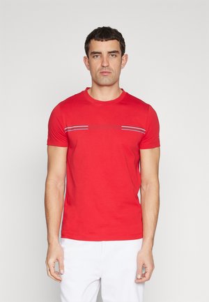 T-shirt in cotone rosso con maniche corte, colletto a girocollo e strisce decorative blu, bianche e rosse sul petto. Presenta un logo ricamato.