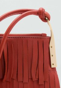Sac à main en cuir rouge avec des franges, un accent en métal doré et une anse structurée. Fermeture éclair en haut.