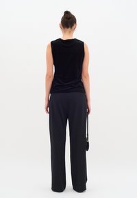 Musthave musta sihhetueta top, millel on pehme sametine tekstuur ja lõdvad mustad püksid, mis omavad lihtsat disaini. Aksessuaaride hulka kuulub väike kott.