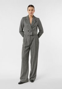 Szary, przycięty blezer w jodełkę z dwoma guzikami oraz spodnie z szerokimi nogawkami. Gładka tkanina o dopasowanym kroju z plisowanymi detalami.