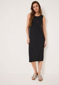 Black sleeveless dress with a relaxed fit, knee-length, crafted from textured fabric. Paired with light grey slide sandals.