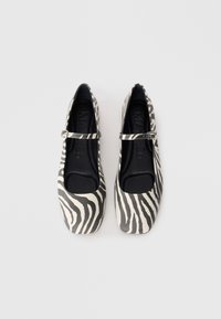 Černobílé zebra vzorované baleríny typu Mary Jane s plochou podrážkou, kulatou špičkou a nastavitelným páskem kolem kotníku. Hladká textura.