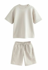 Lysebeige bomuldst-shirt med korte ærmer og ribstrikket halsudskæring, kombineret med matchende shorts med elastik i taljen og sidelommer.