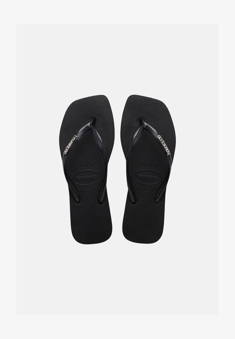 Melni gumijas pludmales čības ar teksturētām zolēm un plānām siksniņām, uz kurām ir Havaianas logotips baltā krāsā uz vienkārša fona.