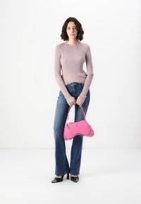 Rosa syntetisk håndveske med buet design; kombinert med en lys lilla ribbestrikket genser og slengjeans i blått. Svart spiss-toe hæler.