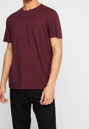 T-shirt en coton bordeaux avec un col rond, des manches courtes et un petit logo brodé sur la poitrine. Coupe simple et décontractée.