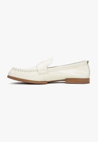 White leather loafers featuring a stitched fringe detail, flat brown rubber sole, and a minimalist design with a prominent overlay strap.