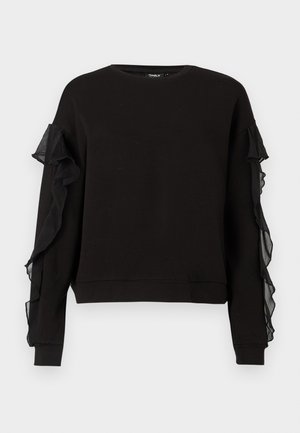 Sudadera negra de manga larga, con acentos de volantes transparentes a ambos lados. Ajuste cómodo con un cuello redondo y puños acanalados.