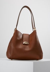 Brown leather handbag with smooth texture, a rounded shape, and a gold hardware accent on the front flap. Features a single strap.