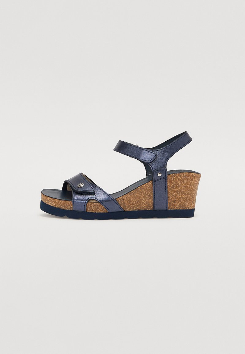 Sandalias de cuña azul marino con plataforma de corcho. Presentan tiras brillantes y un acento decorativo en la parte delantera. Tira ajustable en el tobillo.