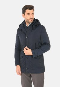 Giacca blu navy con cappuccio, dotata di chiusura frontale con bottoni, due tasche laterali e tessuto liscio e strutturato. Design classico, lunghezza media.