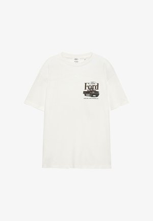 T-shirt en coton blanc présentant un graphique d'un camion Ford vintage avec le texte "Ford" et la phrase "fonctionne comme un camion, roule comme une voiture."
