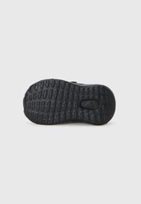 Schwarze Sneakersohle mit einem strukturierten Gummi-Design und einem ausgeprägten Profilmuster für besseren Halt; mit kleinem Adidas-Logo.