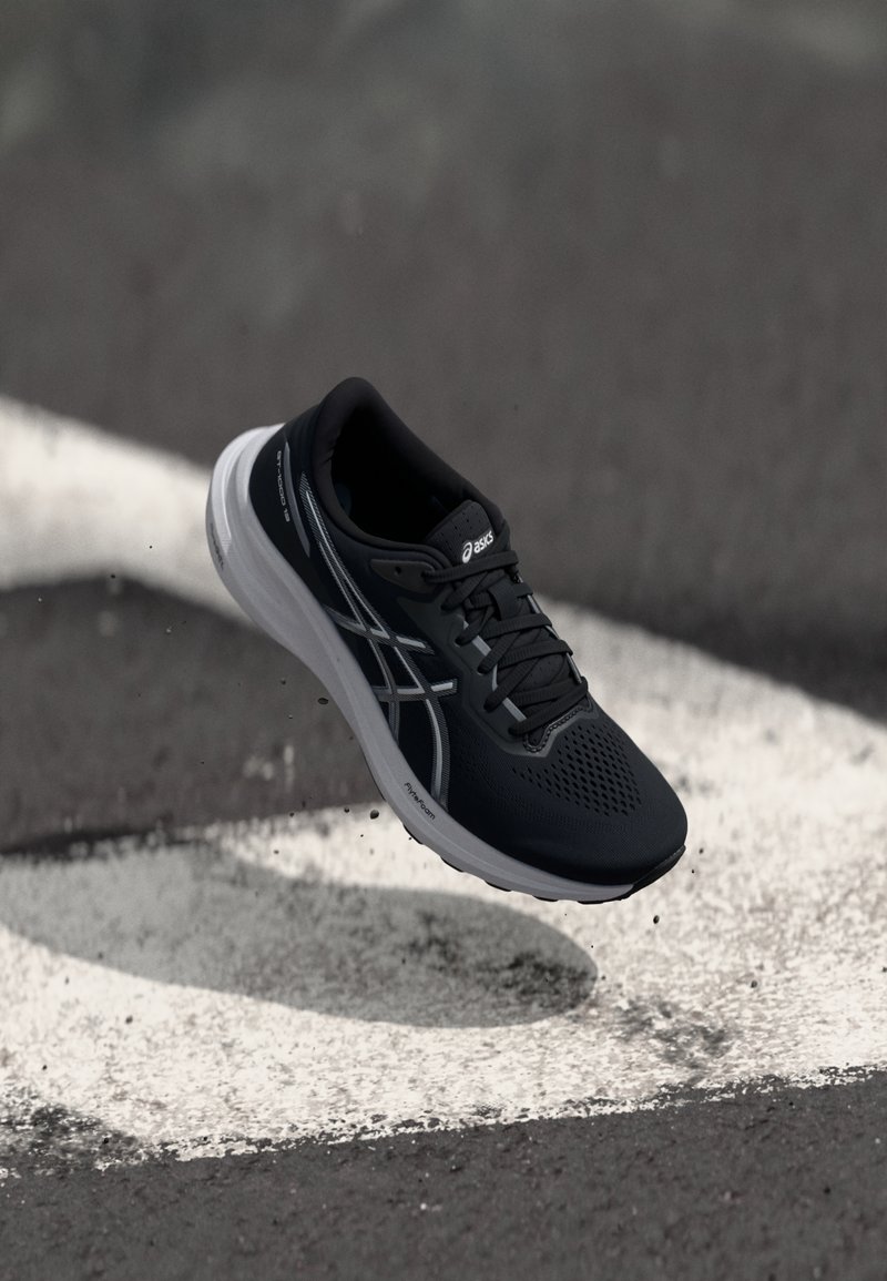 Czarne buty sportowe z siateczkowym wierzchem, białą podeszwą środkową i fakturowaną powierzchnią. Zawierają odblaskowe akcenty oraz sznurowadła. Zaprojektowane do biegania.