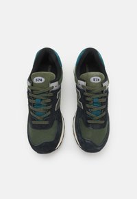 Sn�ěhury New Balance 574 v zelené a námořnické modři. Materiály z jemné kůže a síťoviny, kulaté tkaničky, polstrované límce, s číselnou etiketou na jazyku.