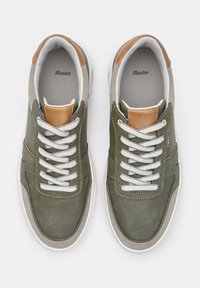 Adidași din piele verde și bej cu un accent maro, șireturi gri, talpă albă, vârf rotunjit și detalii cusute.