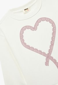 Weißer Sweatshirt mit einem großen, mit Spitze umrandeten rosa Herzdesign. Verfügt über einen gerippten Kragen und eine weiche Stofftextur.