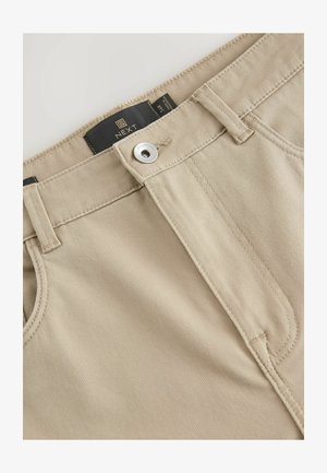 Beige Baumwollhosen mit glatter Textur, Reißverschluss vorn, Knopfverschluss und einem Markenlabel am Hosenbund. Sichtbare Nähdetails.