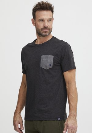 T-shirt pour homme à manches courtes en tissu gris foncé. Présente une poche de contraste gris clair et une petite étiquette de marque sur l'ourlet.