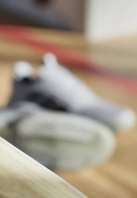 Podeszwa i środkowa część wkładki butów sportowych; jedna jest szara, a druga czarna. Gładkie faktury, widać sznurówki; tło rozmyte.
