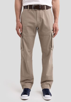 Pantalons cargo beiges avec poches latérales, passants de ceinture et coupe décontractée. Portés avec une ceinture marron et des baskets bleues. Tissu lisse avec une texture subtile.