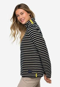 Pull en polaire rayé bleu marine et crème avec un col montant, comportant une accent jaune à l'épaule et un petit logo sur l'ourlet.
