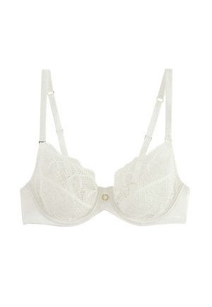 Soutien-gorge blanc en dentelle avec armatures, bretelles réglables et un petit charme doré circulaire au centre avant sur un fond uni.
