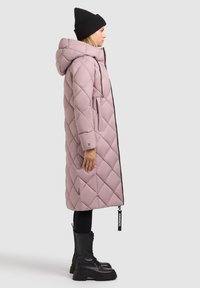Cappotto imbottito rosa con trapuntatura a diamante, cappuccio e chiusura con zip. Abbinate a un berretto nero e stivali neri chunky, che mettono in risalto una silhouette elegante.