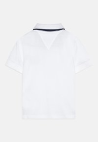 Weißes Polohemd mit einem navyblauen gestreiften Kragen, kurzen Ärmeln und einem klaren, schlichten Design. Verfügt über einen belüftetem Rücken für Atmungsaktivität.