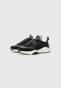 Black suede sneakers with white rubber soles, feature contrasting textures, a padded collar, and black laces. Accented with a logo tag.