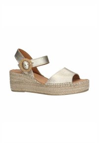 Metallische gouden espadrille wedge sandaal met een open teen, verstelbare enkelband en geweven jute zool. Heeft een gestructureerde bovenkant en een ronde gesp.