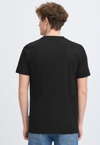 Tricou negru din bumbac cu mâneci scurte și decolteu rotund, prezentat din spate; are o textură netedă și un design simplu.