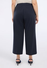 Marineblaue weit geschnittene Hose mit elastischem Bund, aus einem weichen, glatten Stoff gefertigt, mit geradem Schnitt und knöchellang.