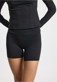 Pantaloni sportivi neri con un design aderente. Realizzati in tessuto elasticizzato, presentano una vita alta e una consistenza liscia per il massimo comfort.