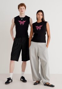Black sleeveless tops with pink butterfly designs, striped shorts, gray sweatpants, and black shoes with white accents. Simple backgrounds.