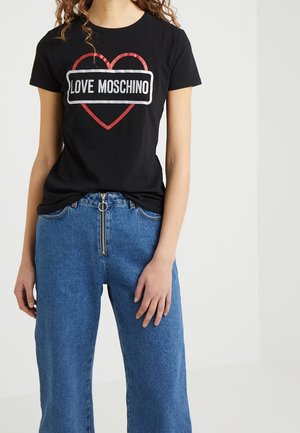 Black cotton t-shirt featuring a heart graphic in red and white with "LOVE MOSCHINO" text. Paired with blue high-waisted wide-leg jeans.
