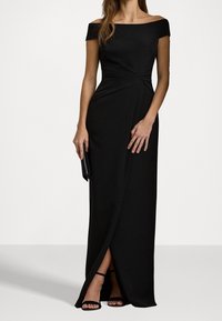 Černé maxi šaty s odhalenými rameny, s přiléhavým korzetem, zkrouceným detailem v pase a vysokým rozparkem. Hladká látka a elegantní silueta.